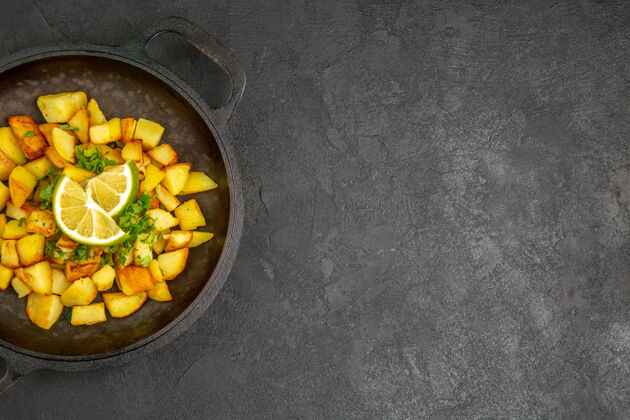 锅顶视图美味的煎炸土豆内锅柠檬片在黑暗的表面玉米果仁食物