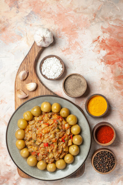 一餐烤茄子沙拉的顶视图放在盘子上的砧板上不同的香料放在碗里的裸体表面烤食品切