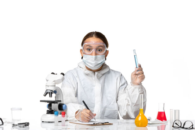 医学正面图：女医生穿着防护服 戴着口罩 拿着装有溶液的烧瓶 在白色背景上写着冠状病毒大流行视图实验室外套西装