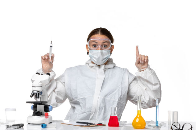 外套正面图：穿着防护服 戴着口罩的女医生拿着注射用的白色背景病毒药柯维德-大流行保持实验室外套实验室