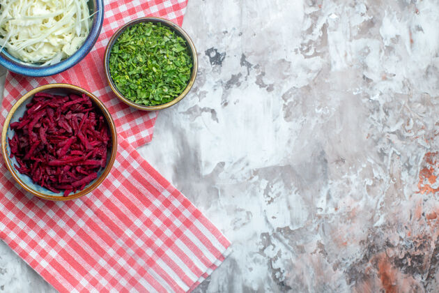 食物白色表面上的甜菜和绿色切片卷心菜俯视图健康沙拉晚餐