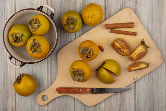 有机有机柿子水果的俯视图在一个木制的厨房板上 肉桂棒和刀放在一张灰色的木桌上板观点肉桂