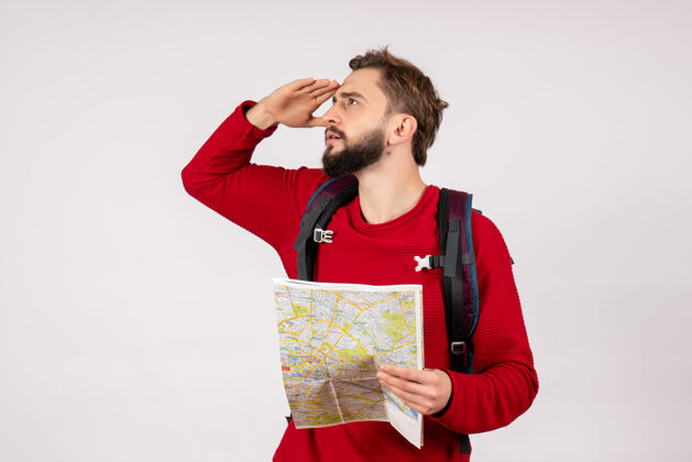 城市正面图年轻男性游客背着背包在白墙飞机上探索地图城市度假情感人文旅游路线路线地图背包