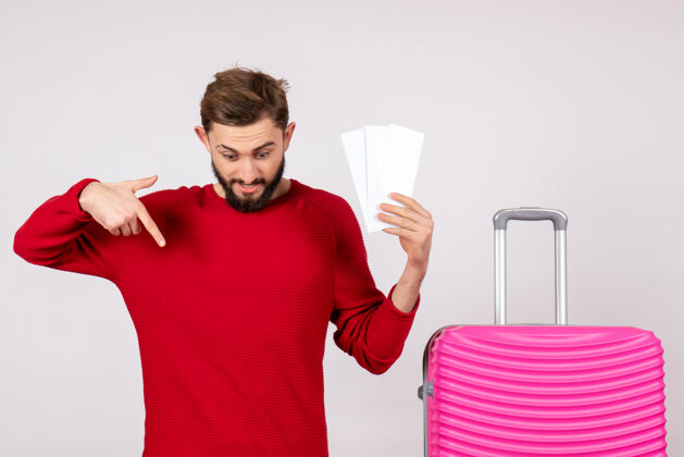 年轻的男性正面图：年轻男子手拿粉红包 手拿机票上白墙航程旅游度假情感照飞行微笑情感