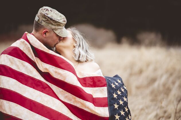 亲吻一个美国士兵裹着美国国旗亲吻他亲爱的妻子的浅焦镜头国家美国人伙伴