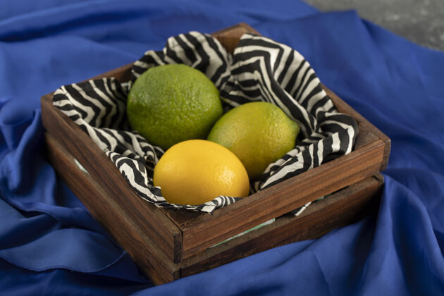 美味蓝布上放着三个柠檬的木篮柑橘木头篮子