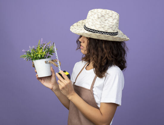 人想想年轻的女园丁穿着制服戴着园艺帽用卷尺量花盆里的花园艺思想花盆
