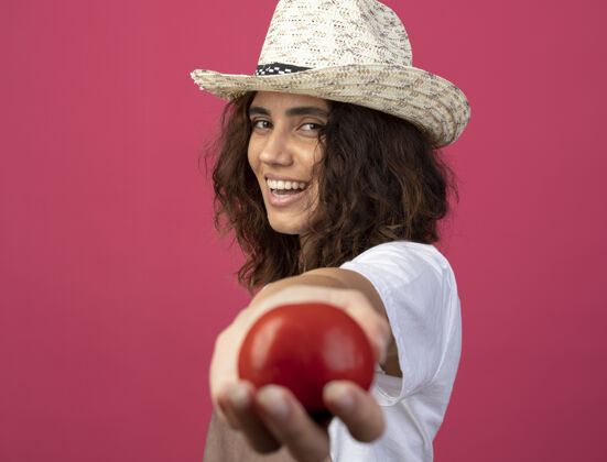 女人身着制服 面带微笑的年轻女园丁戴着园艺帽 手里拿着西红柿帽子制服人
