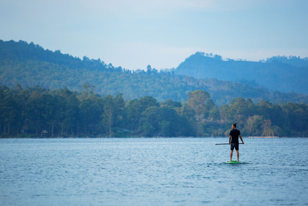 湖泊一个男人在湖边骑冲浪板冲浪娱乐活跃