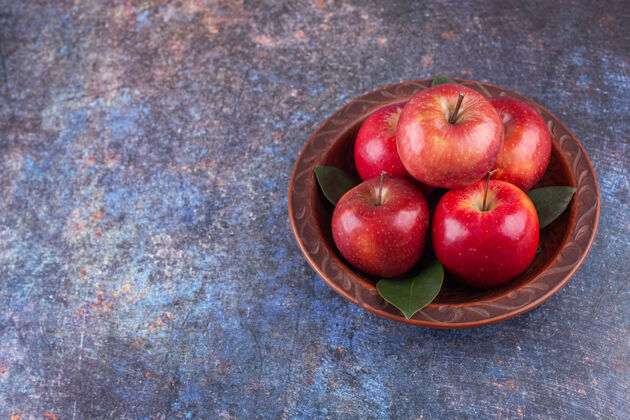 有机闪亮的红苹果 石头背景上有绿叶背景有光泽水果