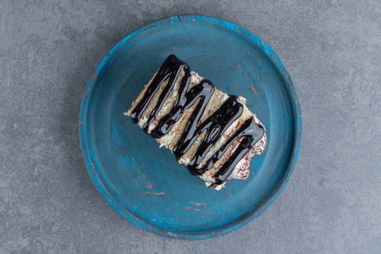 软在蓝色盘子上放一块奶油蛋糕和巧克力片美食招待