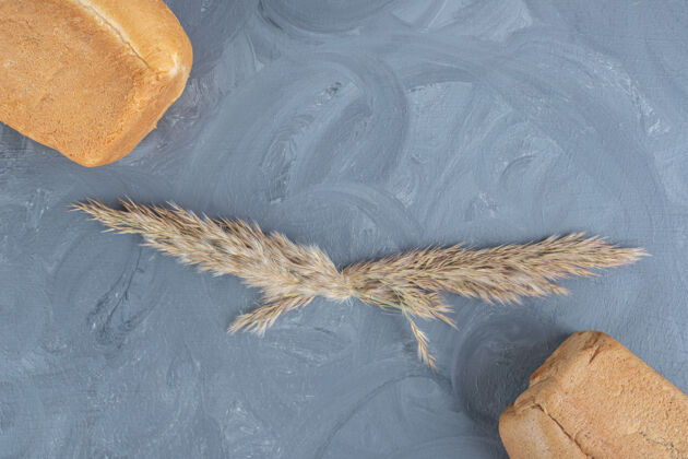 烘焙大理石背景上夹着一块块面包 中间夹着羽毛草茎面粉小麦背景