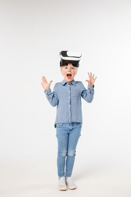 创新对未来感到惊讶穿着牛仔裤和衬衫的小女孩或孩子 戴着虚拟现实耳机眼镜 隔离在白色工作室背景上尖端技术的概念 视频游戏 创新未来软件科技