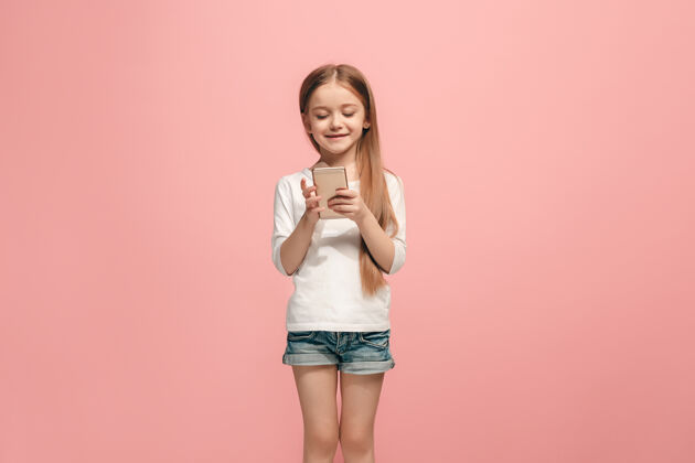 满意快乐的少女站在粉红色的墙上微笑着短信脸漂亮