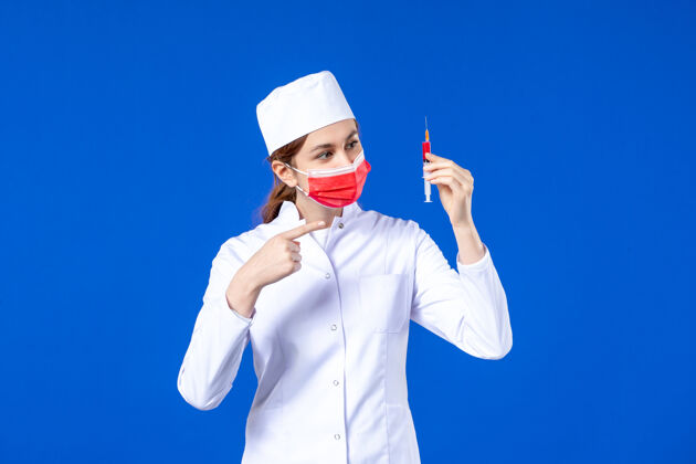 女护士正面图：身穿白色医疗服的女护士 戴着红色面罩 手上拿着蓝色针剂注射流行病男人