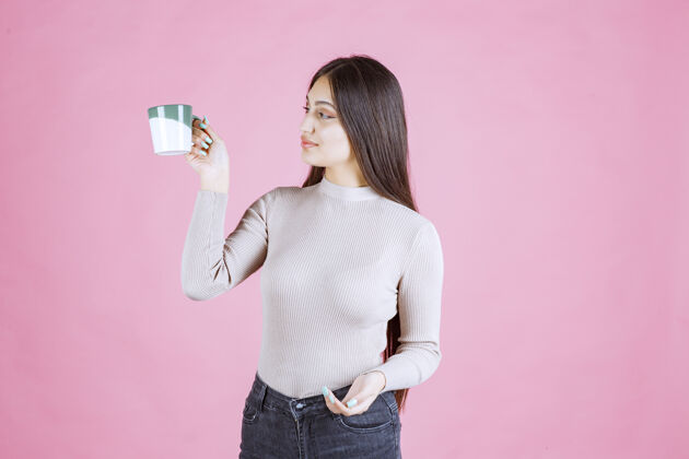 卡布奇诺女孩拿着一个白绿色的咖啡杯 感觉很积极成人女人人