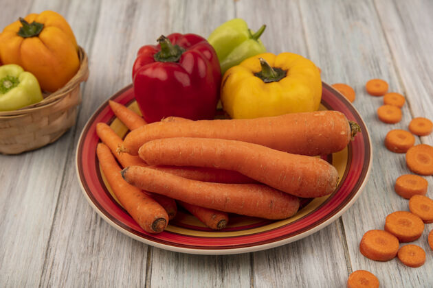 烹饪健康的甜椒与胡萝卜盘上的顶视图黄色甜椒桶与切碎的胡萝卜隔离在一个灰色的木制背景自然健康新鲜