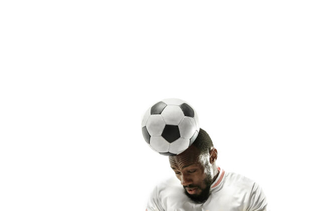训练情绪化的非洲男人踢足球的特写镜头用头在隔离的白墙上击球足球 运动 面部表情 人类情绪 健康的生活方式概念复制空间足球球员人