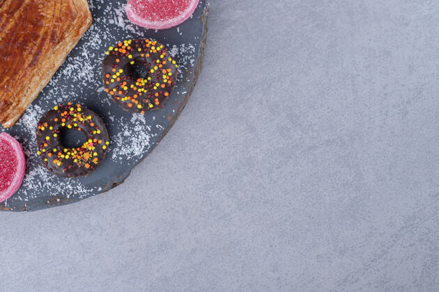 烘焙食品一口大小的甜甜圈和marmelade围绕在大理石表面的木板上的kyata甜点糕点美味