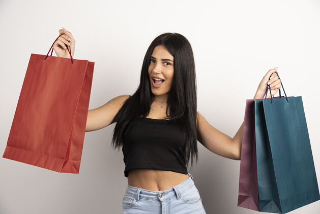 持有快乐的女人提着米色背景的购物袋高品质的照片携带顾客包