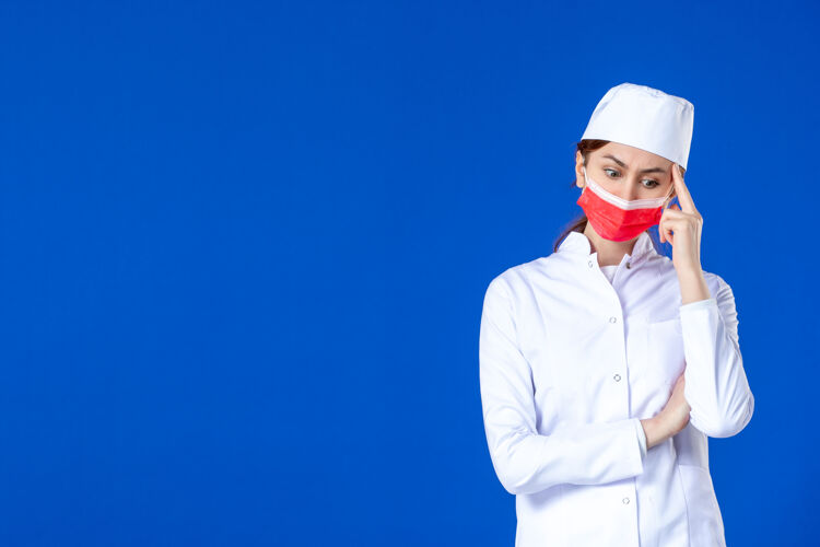 成人正面图蓝色墙上戴着红色防护面具的年轻护士 穿着医疗服视图防护蓝色