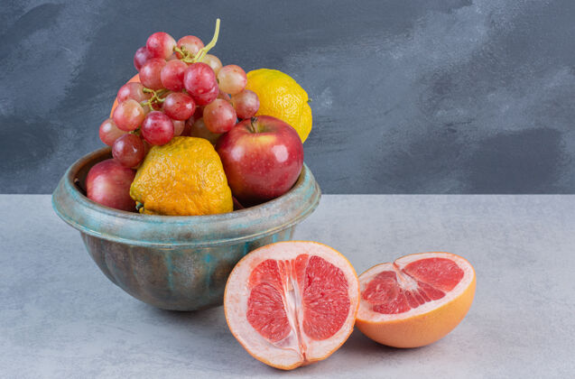 不同新鲜的有机水果放在碗里 灰色背景多餐桌配料