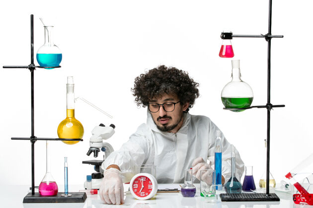 实验室白壁上工作过程中身着特殊服装的年轻男科学家的正面图化学实验室烧杯