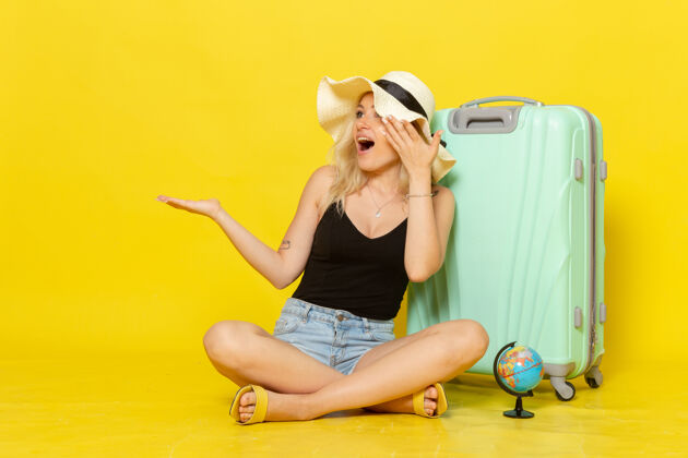 年轻正面图年轻的女性坐在黄色的地板上带着她的包旅行度假航海旅行阳光风景美丽成人