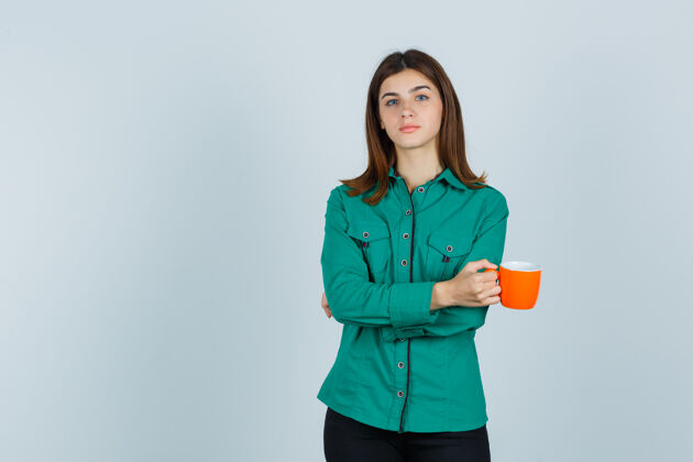 女性年轻的女士拿着一杯橘色的茶 穿着衬衫 看起来很自信 正对着前方信心家庭清洁