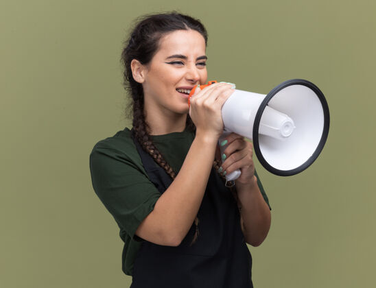 制服微笑着看着身边穿着制服的年轻女理发师在橄榄绿墙上用扬声器讲话扩音器年轻理发师