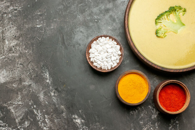 射击棕色碗里的奶油西兰花汤和灰色桌子上的不同香料晚餐不同的健康