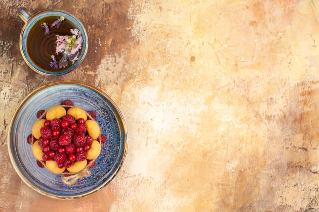 杯子新鲜出炉的礼品蛋糕和水果放在蓝色托盘上 一杯茶放在五颜六色的桌子上烹饪饮食水果