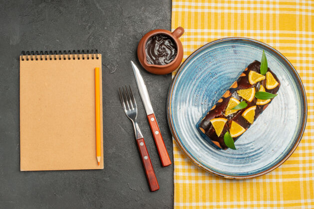 笔记用橘子和巧克力装饰的美味蛋糕 配有刀叉和笔记本蛋糕纸笔记本