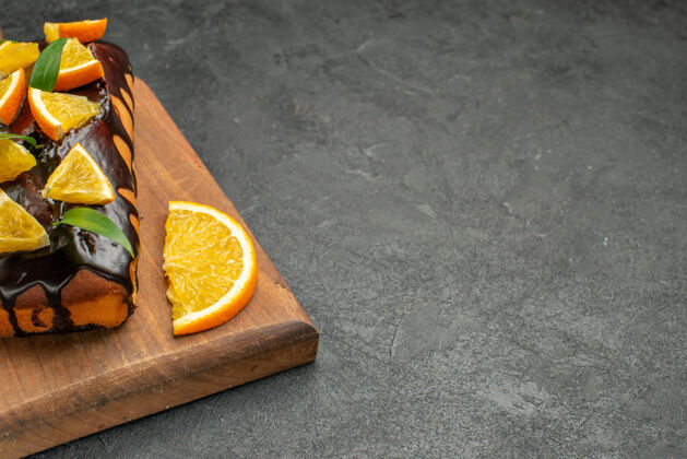 柑橘美味的蛋糕装饰着橘子和巧克力在黑桌子的砧板上新鲜切片减肥
