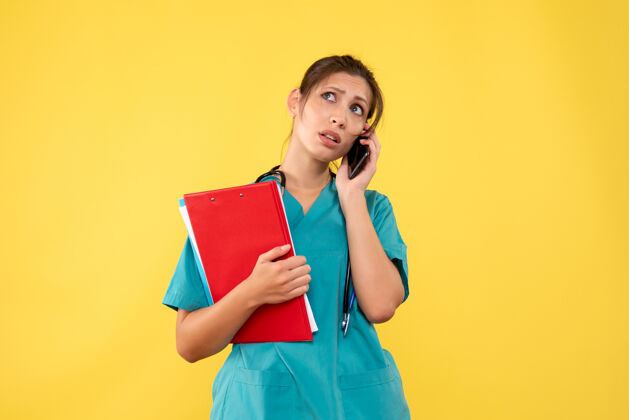 情绪正面图黄色背景下穿着医用衬衫的女医生在讲电话人健康衬衫