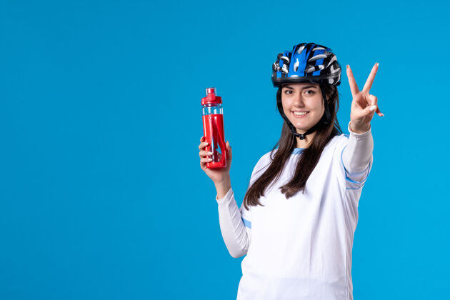 头盔前视图穿着运动服的年轻女性 蓝色墙上戴着头盔人获胜者年轻女性