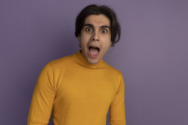 穿惊讶的年轻帅哥穿着黄色高领毛衣隔离在紫色的墙上与复制空间惊喜高领毛衣毛衣