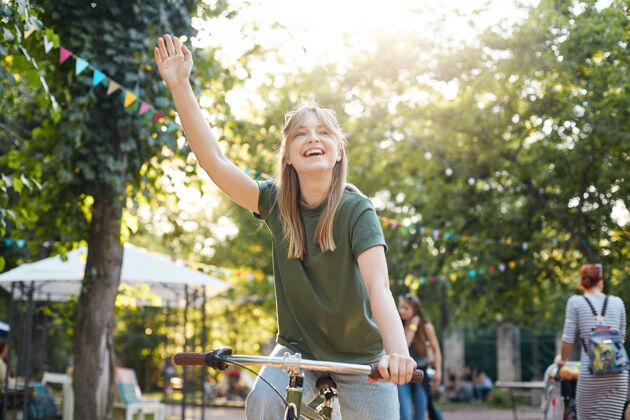 绿色在公园里骑自行车的女人城市公园里一个骑自行车的年轻女人的画像金发无忧无虑乐趣