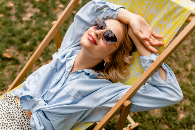 衣服迷人的金发微笑的女人坐在躺椅上穿着夏天的衣服乐趣休息积极