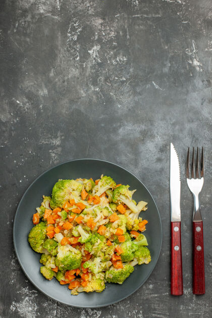 蔬菜健康餐 西兰花和胡萝卜放在盘子里 刀叉放在灰色的桌子上厨具午餐刀