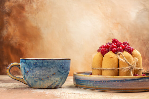 碗在混色桌上的蓝色杯子里 可以看到新鲜出炉的软蛋糕 水果和茶水果饮食健康