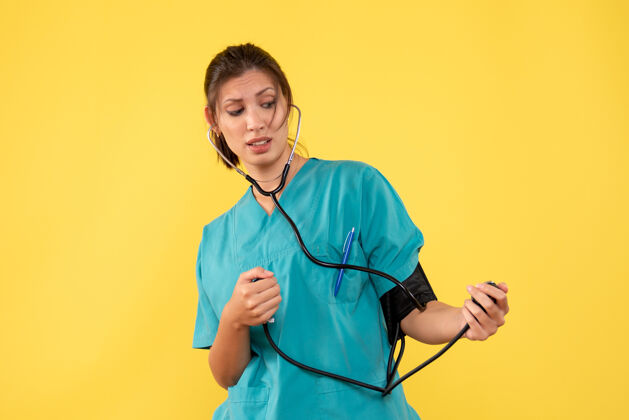 药前视图穿着医用衬衫的女医生正在检查黄色背景上的压力医生压力人