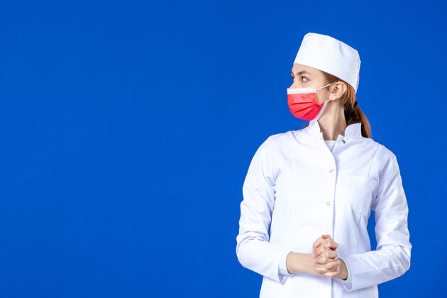红色正面图蓝色墙上戴着红色面罩的年轻护士 穿着医疗服专业人成人
