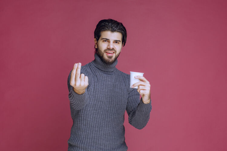 口味男人拿着一个一次性咖啡杯 做着享受的手势拇指聪明成人