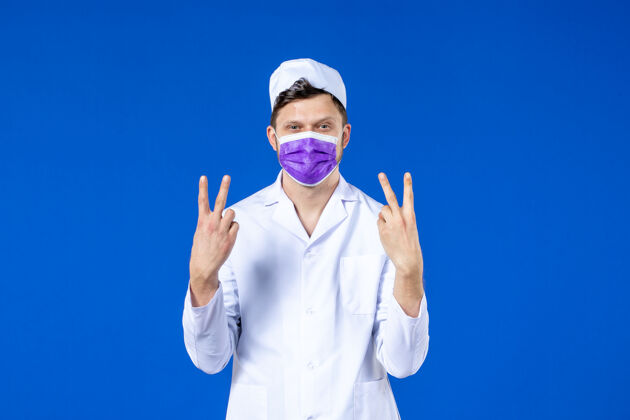 男医生身穿医疗服 戴着紫色面罩的男医生的正视图 蓝色的药品病毒衣服