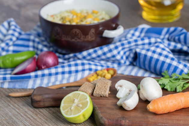 油在桌布上放着蔬菜和汤匙的一锅面条平底锅板胡椒