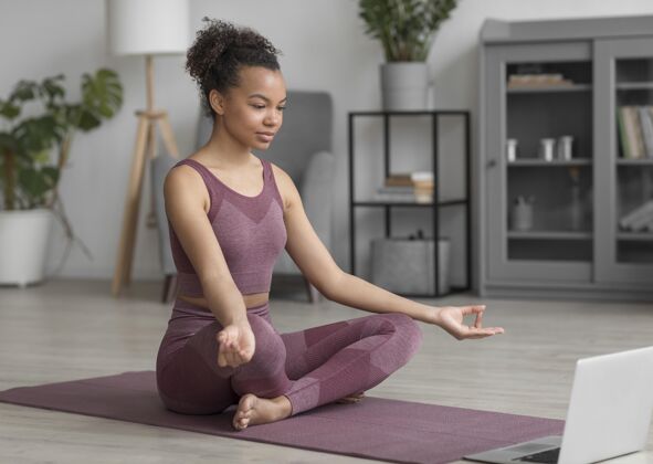 平衡健身女士在家里用瑜伽垫做瑜伽房子人体笔记本电脑
