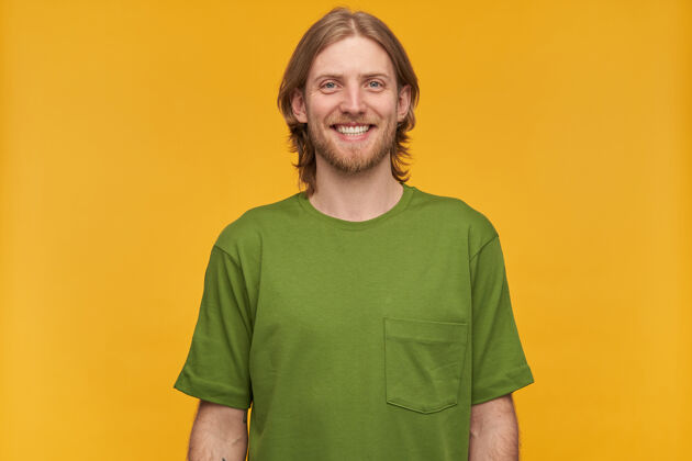 外表一幅英俊开朗的男性肖像 金发碧眼 蓄着胡须身穿绿色t恤面带微笑人物和情感概念隔着黄墙隔离成人室内装束