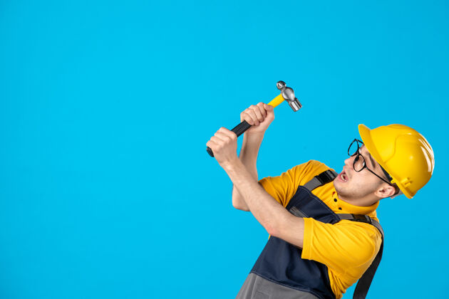 男工人穿着黄色制服的男工人的正视图 锤子放在蓝色制服上锤子表面服务