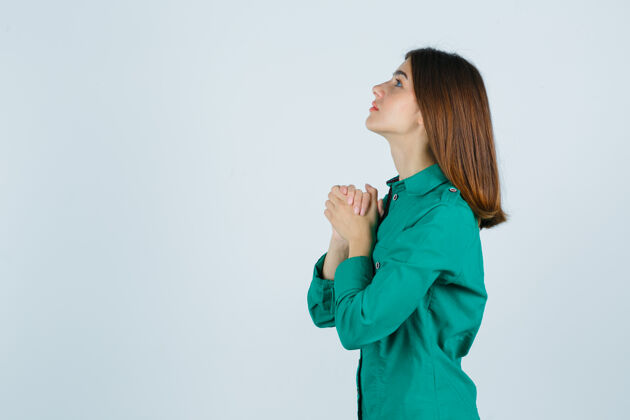 希望之家身穿绿色衬衫的年轻女性双手合十祈祷 看上去充满希望扣成人千禧年的心灵